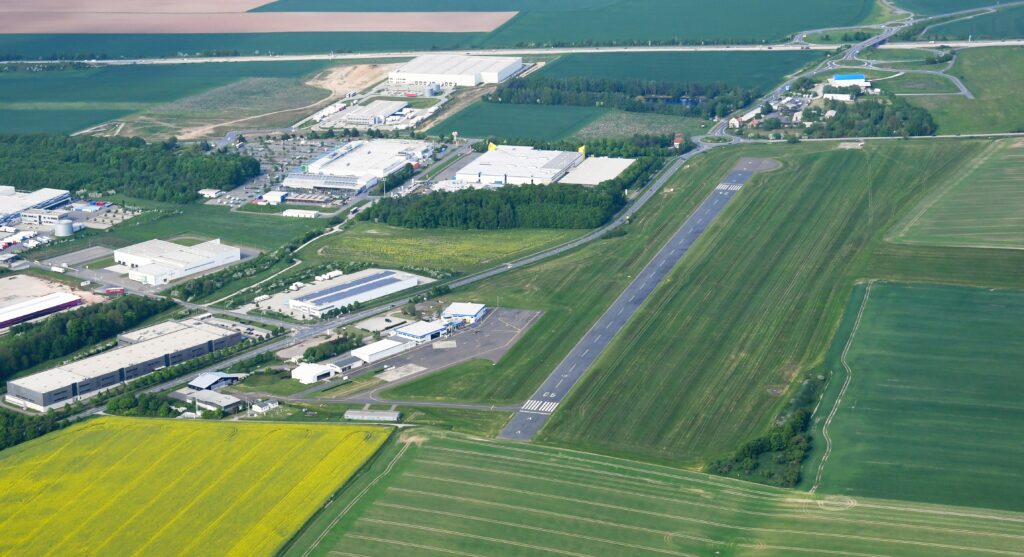 Luftaufnahme des Flugplatzes Gera-Leumnitz mit Asphaltbahn, Vorfeld und umliegender Landschaft